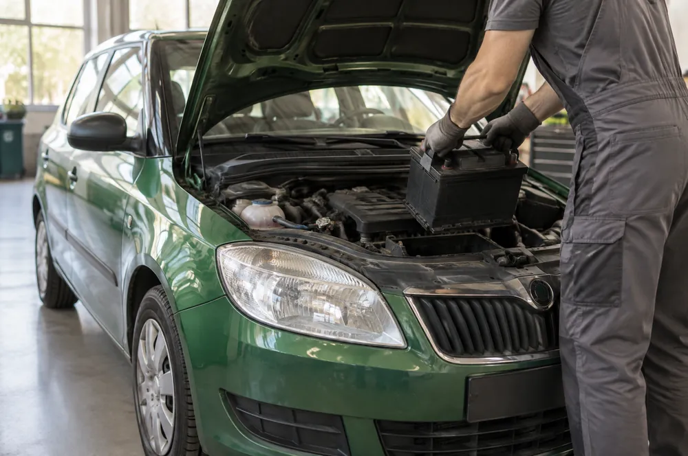 Technik vyjímá akumulátor z motorového prostoru Škody Fabie v hale zpracovatele