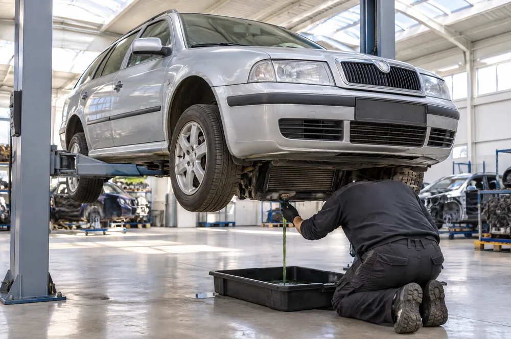 Technik vypouští chladicí kapalinu z chladiče Škody Octavie Combi na zvedáku